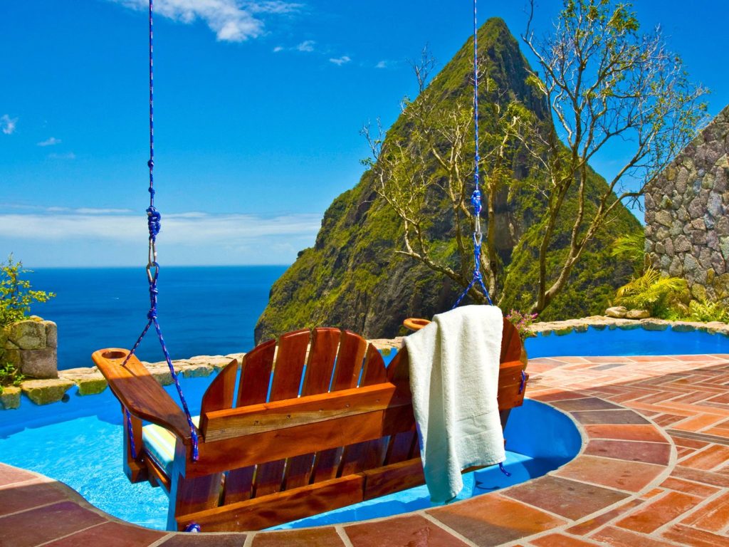 A swing chair hovering over a pool and overlooking the ocean view at Ladera, St. Lucia