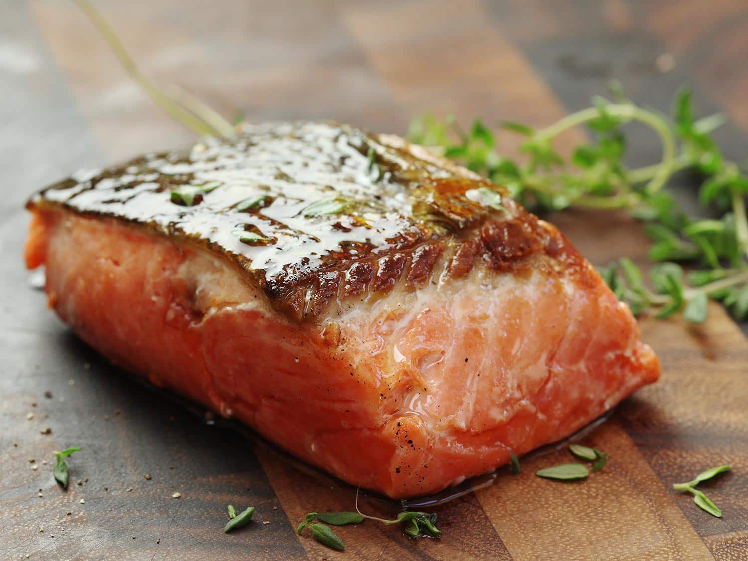 Fried salmon filet placed on a wooden chopping board