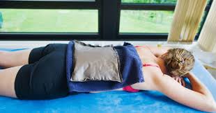 Woman lying on her stomach with a heat pack applied to her lower back