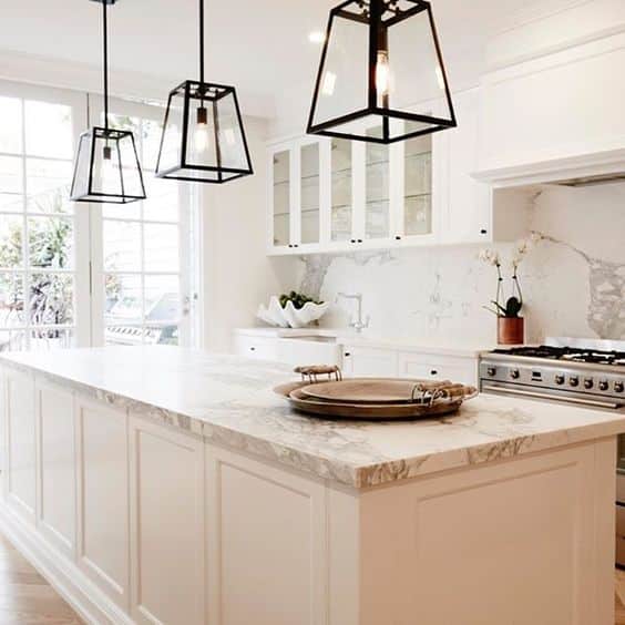 A kitchen displaying checkered stone and black pendant lights