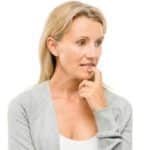 Middle aged woman pressing a finger to her lower lip looking concerned