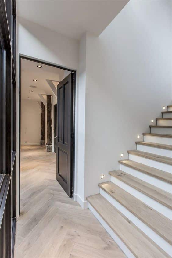 The bottom of a staircase with light wooden floors