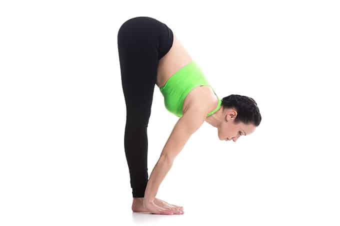 A woman standing with her legs straight, bent at the waist and touching her feet.